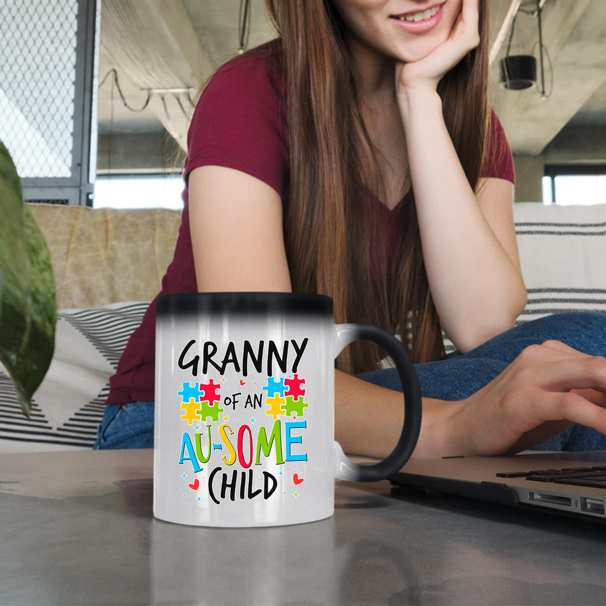 Woman at a laptop with the Granny of an Au-Some Child colour changing mug