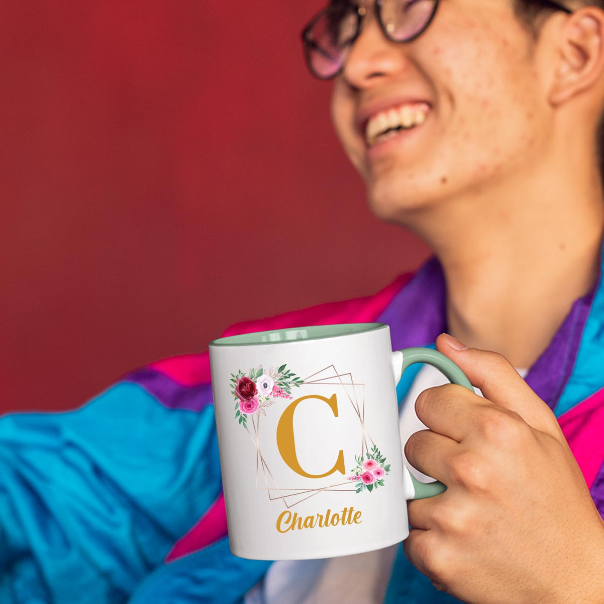 Person laughing while holding a lime handle mug with a gold initial in a floral frame and an example name
