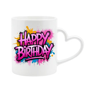 White heart-handle mug with “Happy Birthday” in pink graffiti letters with orange and blue paint splashes