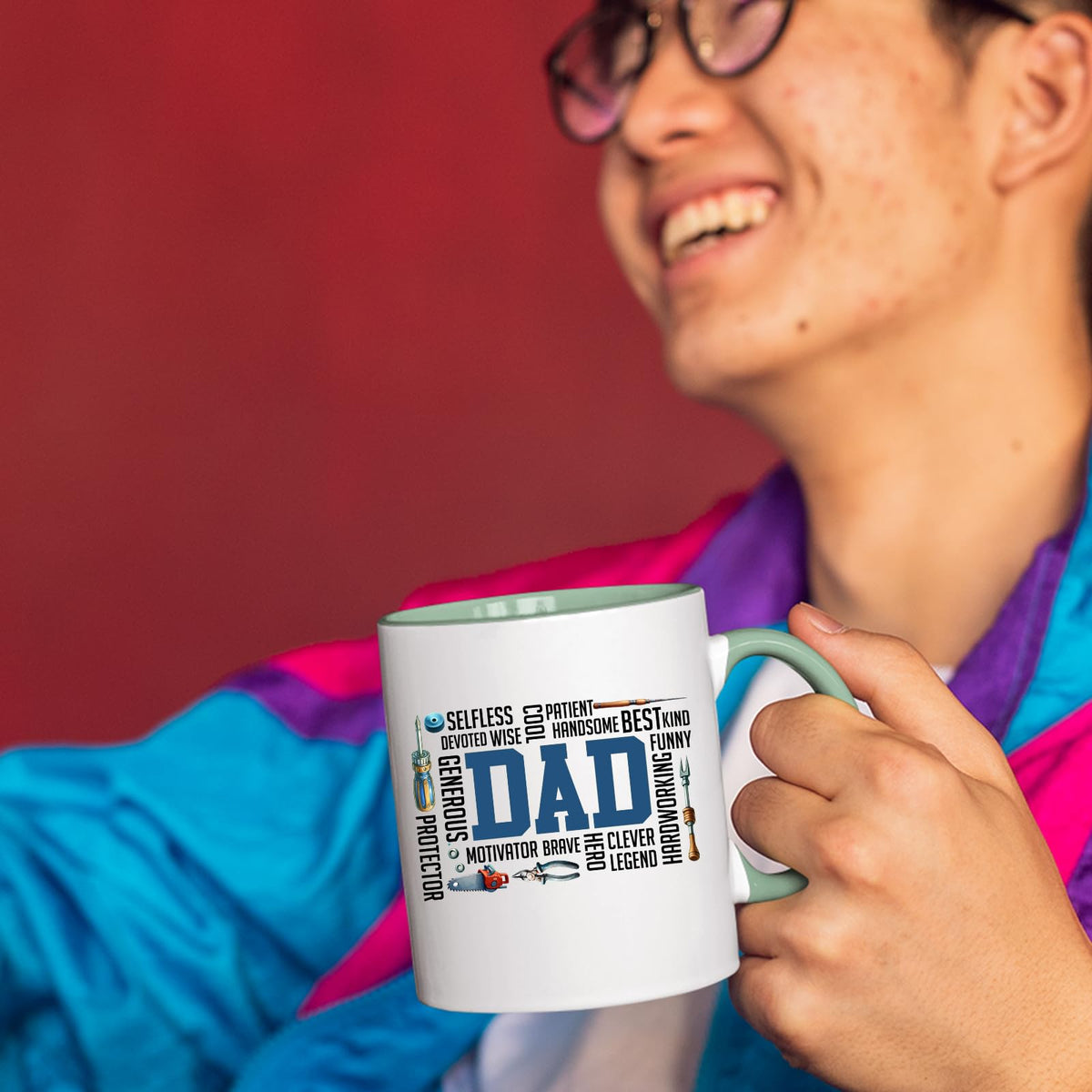 Smiling person in a colourful jacket holding the DAD word cloud mug with a light green handle