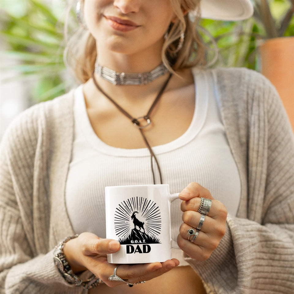 Woman in a cardigan holding the GOAT Dad mug