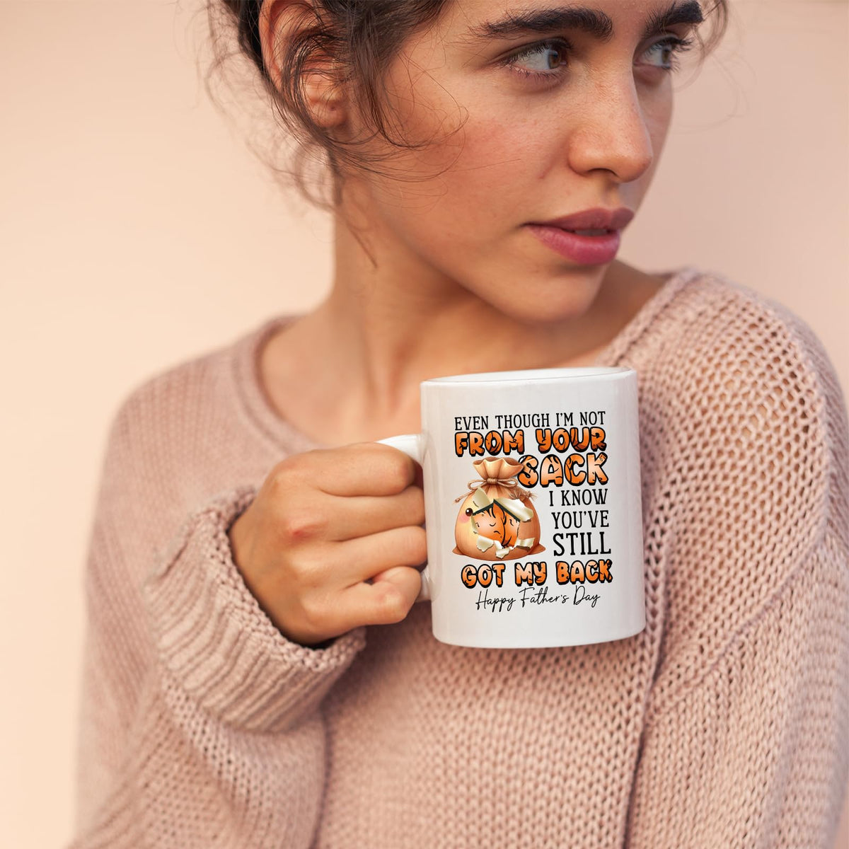 Woman in a pink jumper holding the Not From Your Sack mug