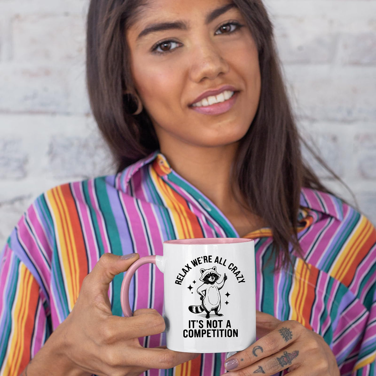 Woman in a striped shirt holding the Relax We’re All Crazy raccoon colour handle mug