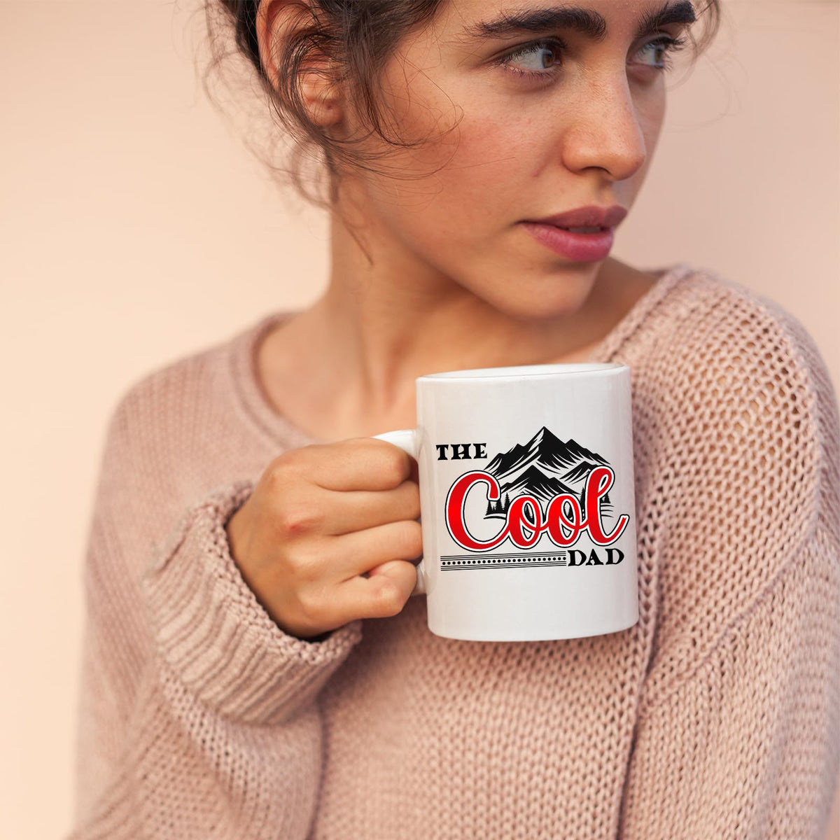 Woman in a pink jumper holding the The Cool Dad mountains mug