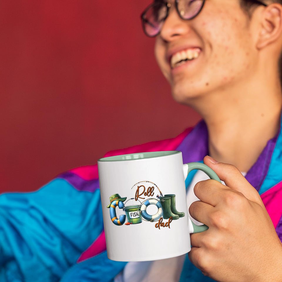 Smiling person in a colourful jacket holding the Reel Cool Dad mug with a light green handle