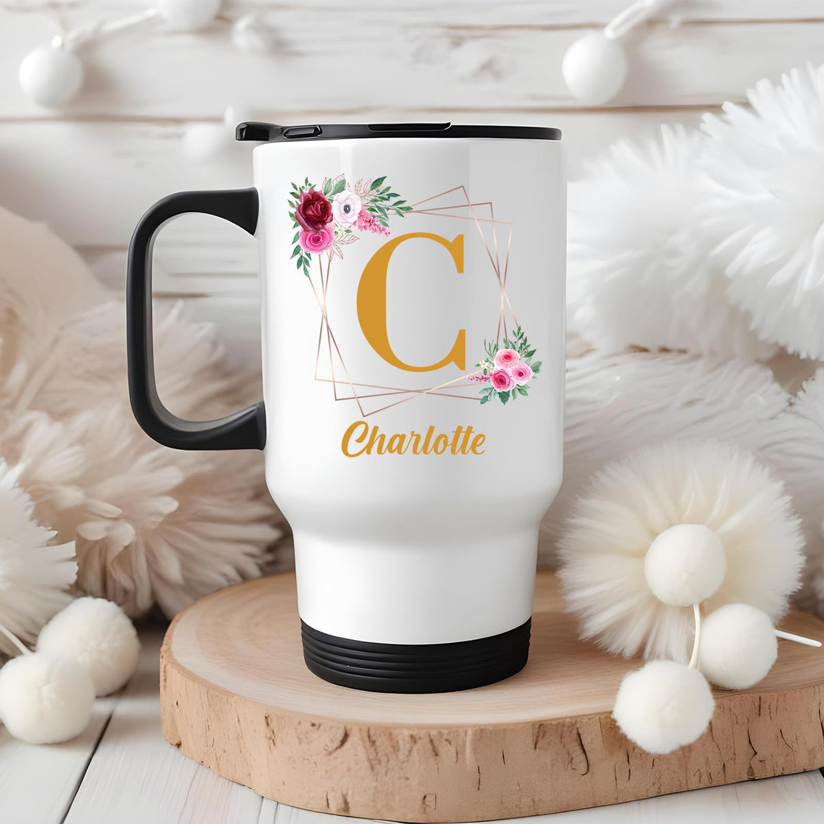 Travel mug with a gold initial in a floral frame and an example name in a cosy winter setting