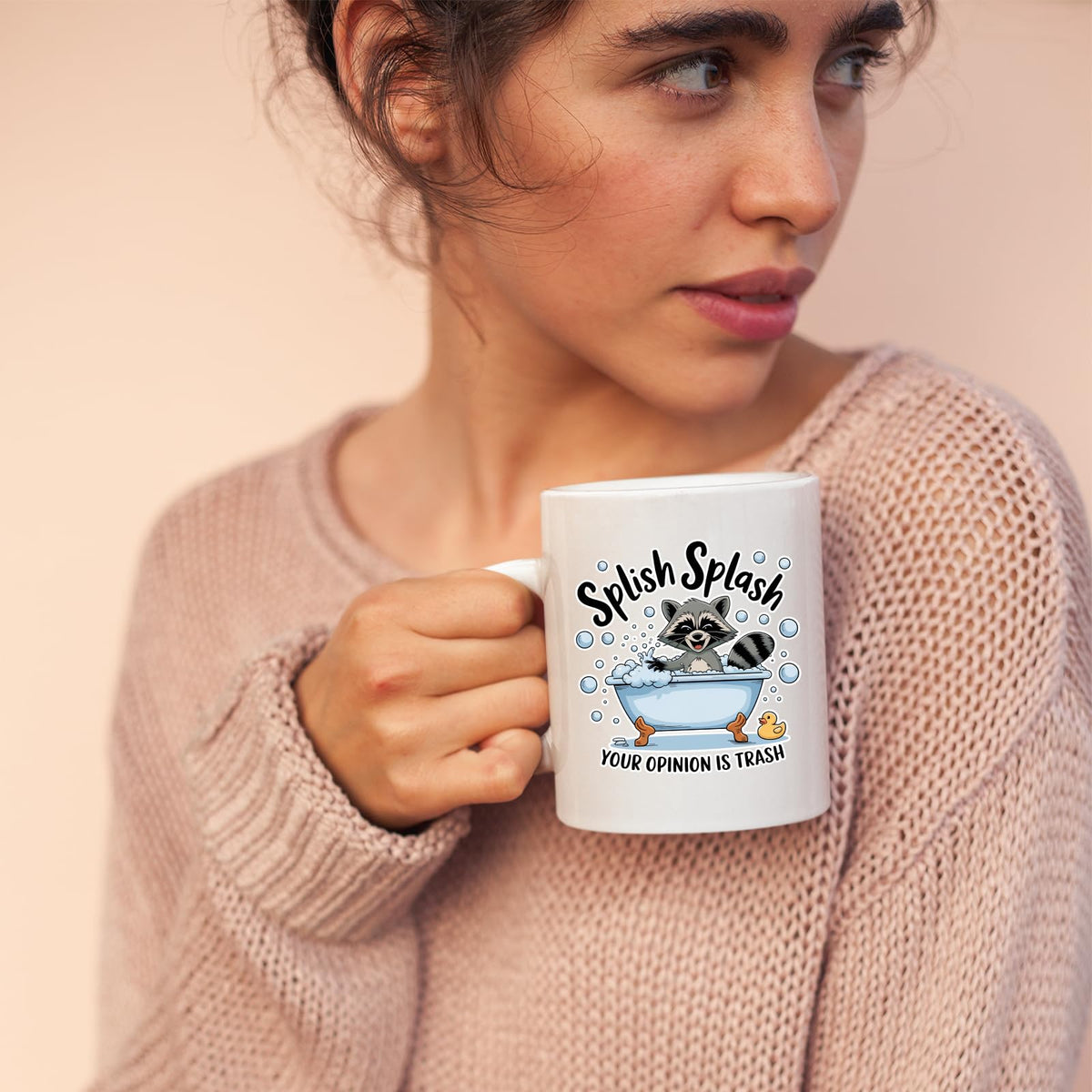 Woman in a pink jumper holding the Splish Splash raccoon mug