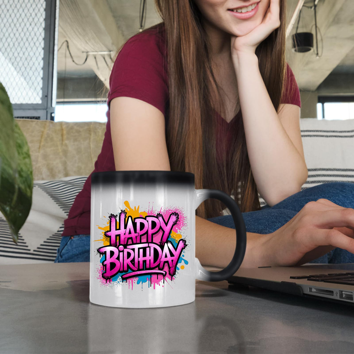 Woman at a laptop with the Happy Birthday pink graffiti splash colour changing mug