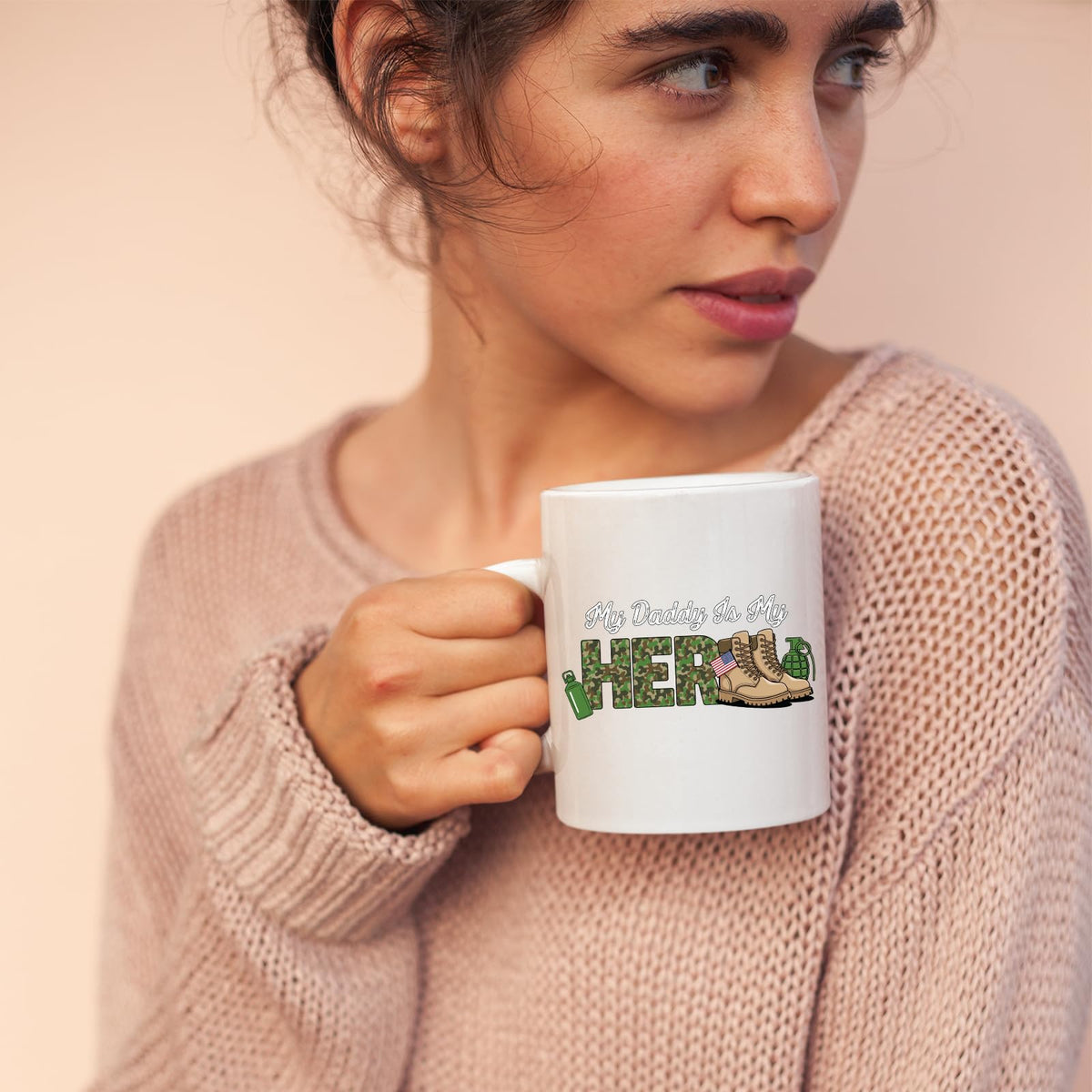 Woman in a pink jumper holding the My Daddy Is My Hero military mug