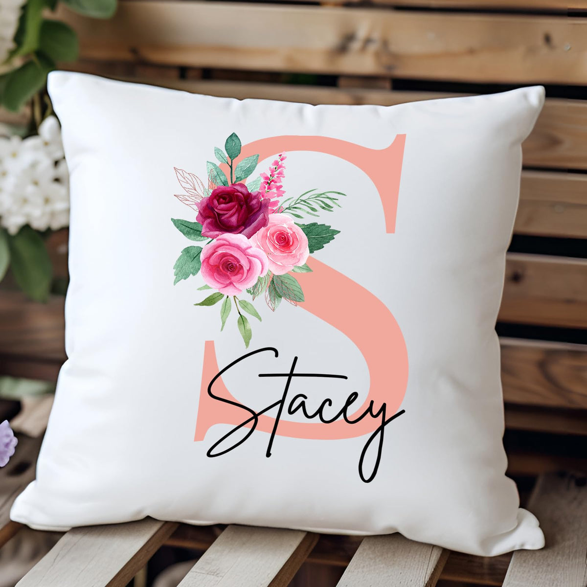 Cushion with a blush pink initial with roses and an example name on a wooden bench