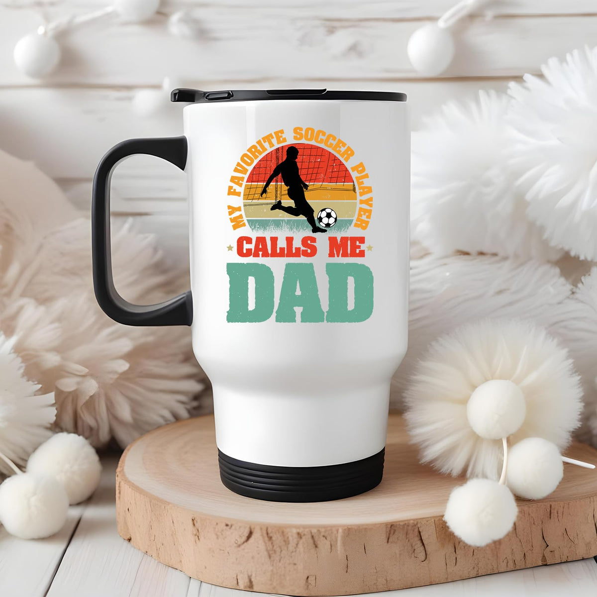 Soccer Dad travel mug on a wooden slice with white pom-poms