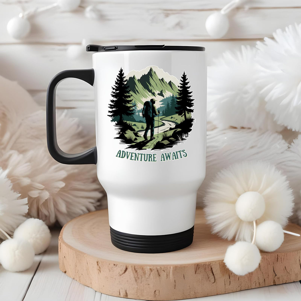 Adventure Awaits hiker travel mug on a wooden slice with white pom-poms