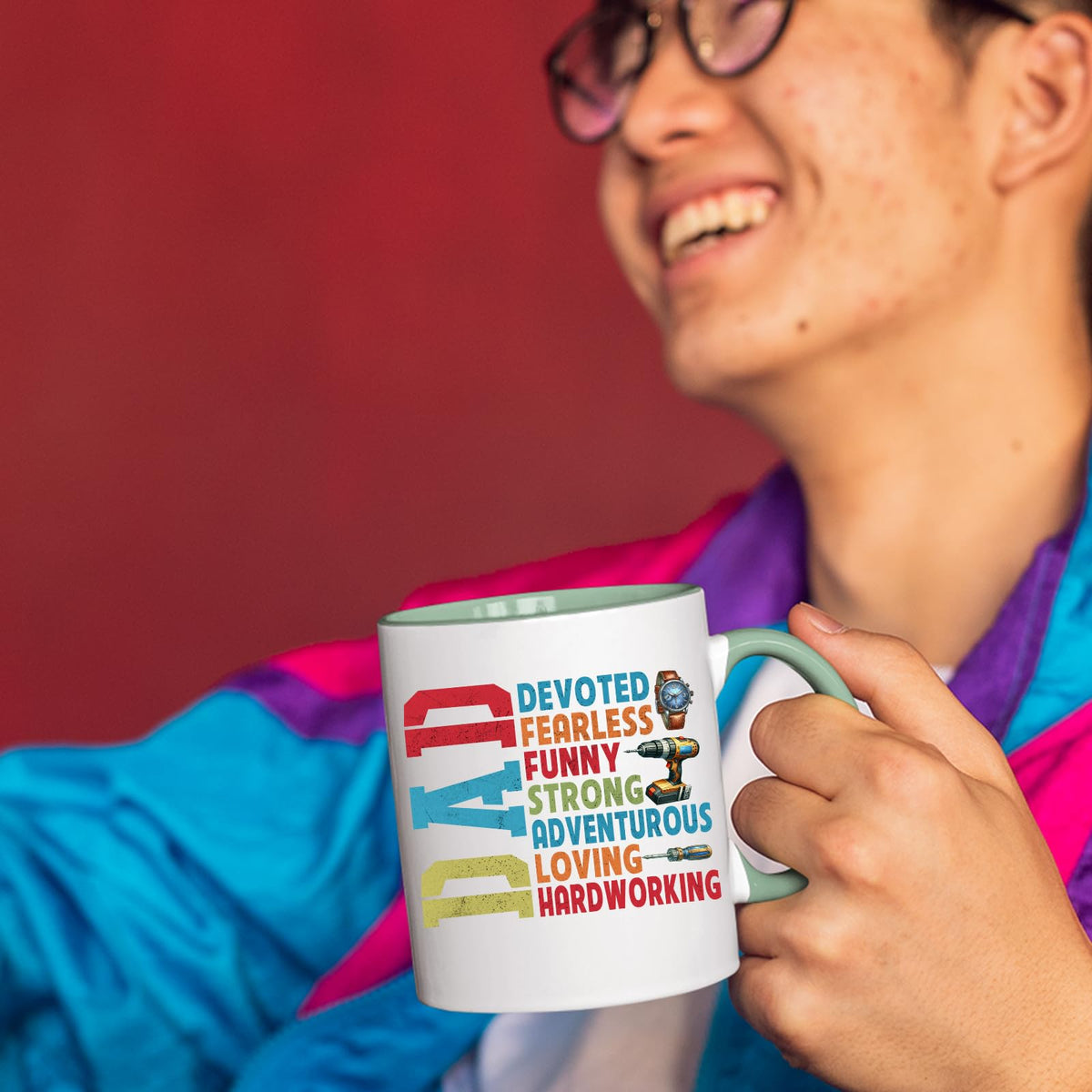 Smiling person in a colourful jacket holding the DAD Devoted mug with a light green handle