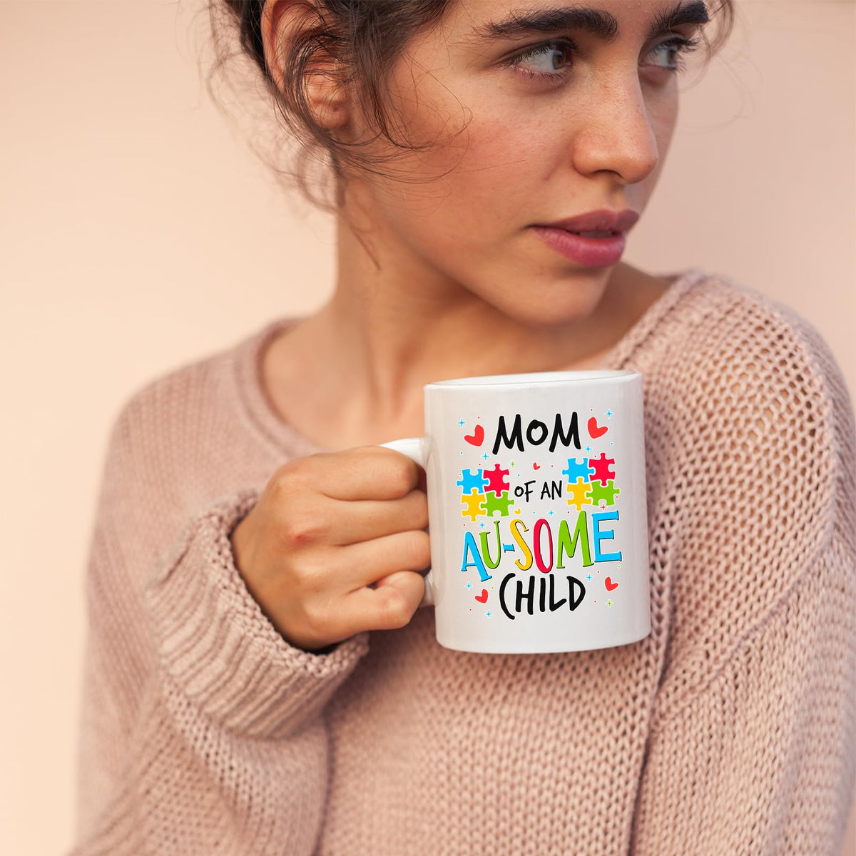 Woman in a pink jumper holding the Mom of an Au-Some Child mug