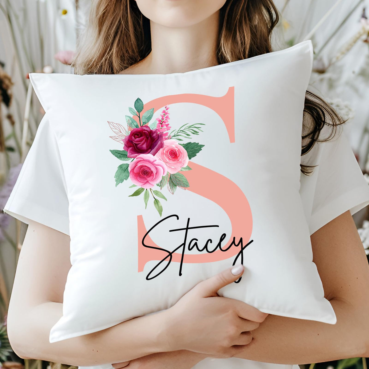 Woman holding a cushion with a blush pink initial with roses and an example name