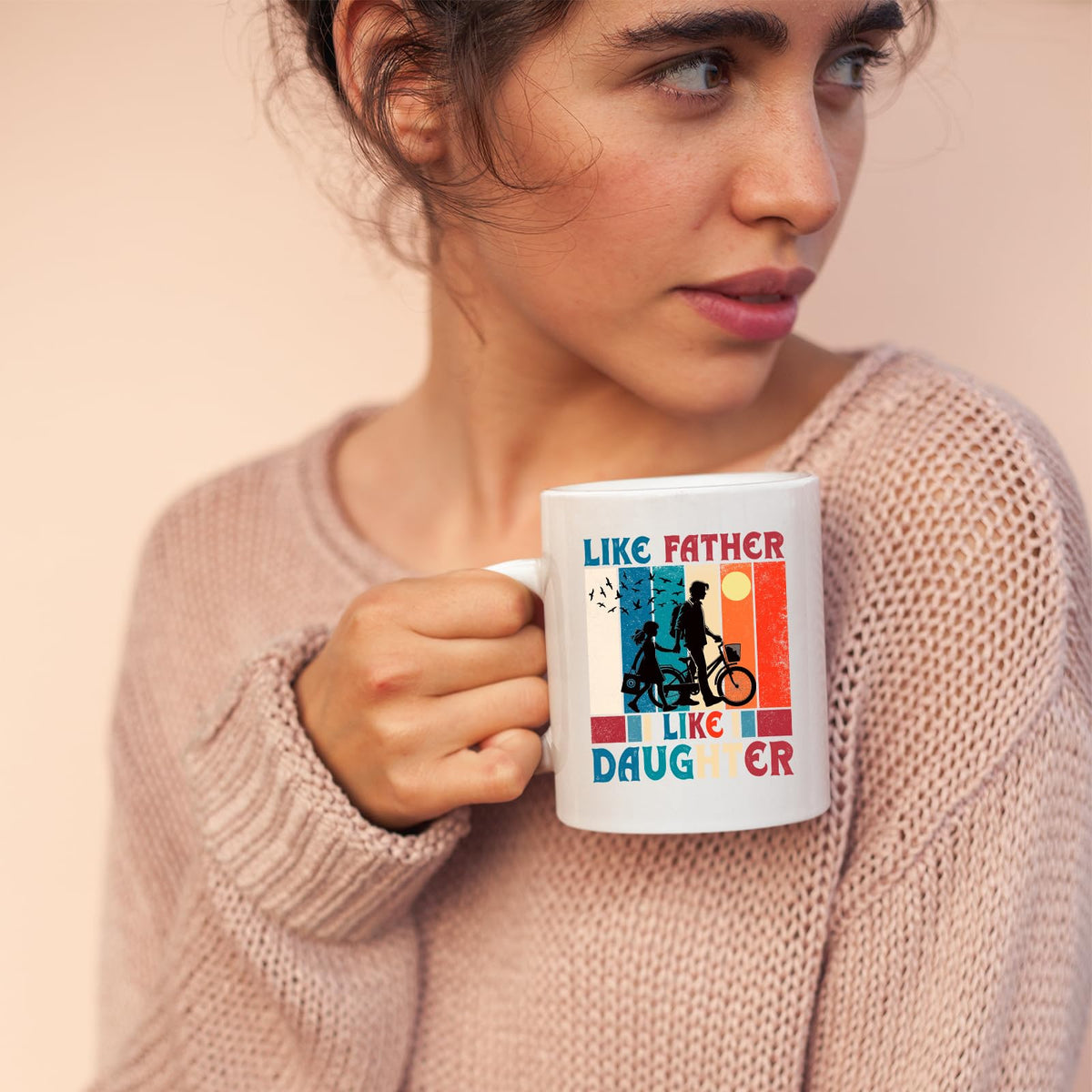 Woman in a pink jumper holding the Like Father Like Daughter mug