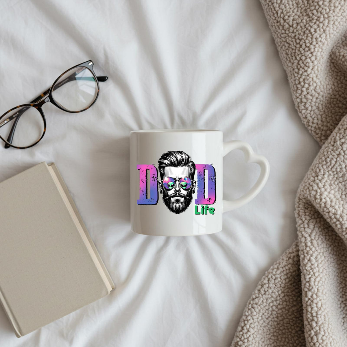 Dad Life bearded dad heart-handle mug on a bed beside glasses and a book