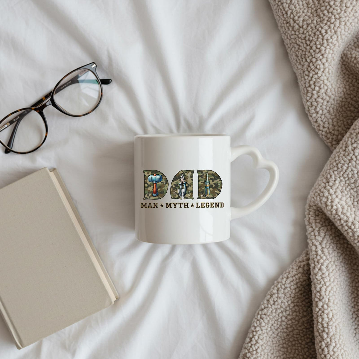 Dad Man Myth Legend tools heart-handle mug on a bed beside glasses and a book