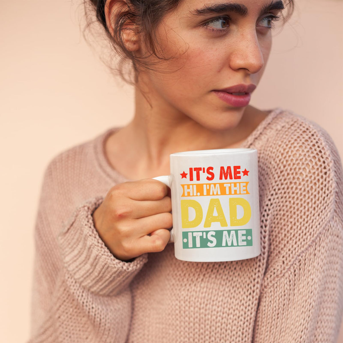 Woman in a pink jumper holding the It’s Me Hi I’m the Dad mug