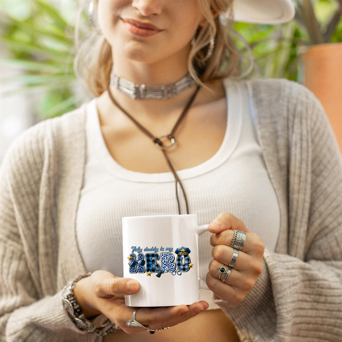 Woman in a cardigan holding the My Daddy Is My Hero police mug