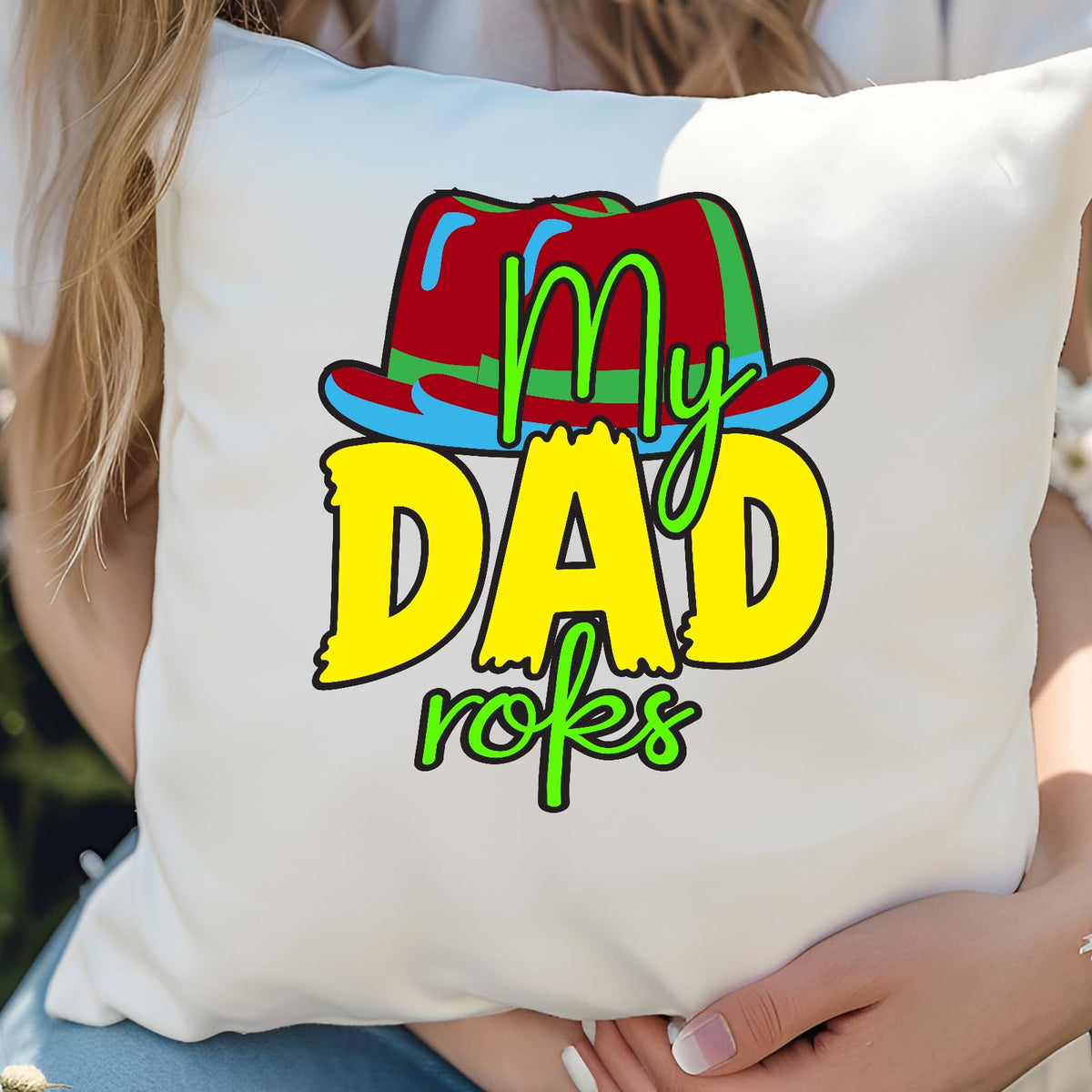 Woman hugging a cushion with the colourful My Dad Rocks hat design