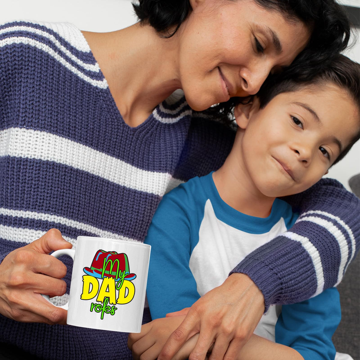 Mother and son cuddling with a mug with the colourful My Dad Rocks hat design
