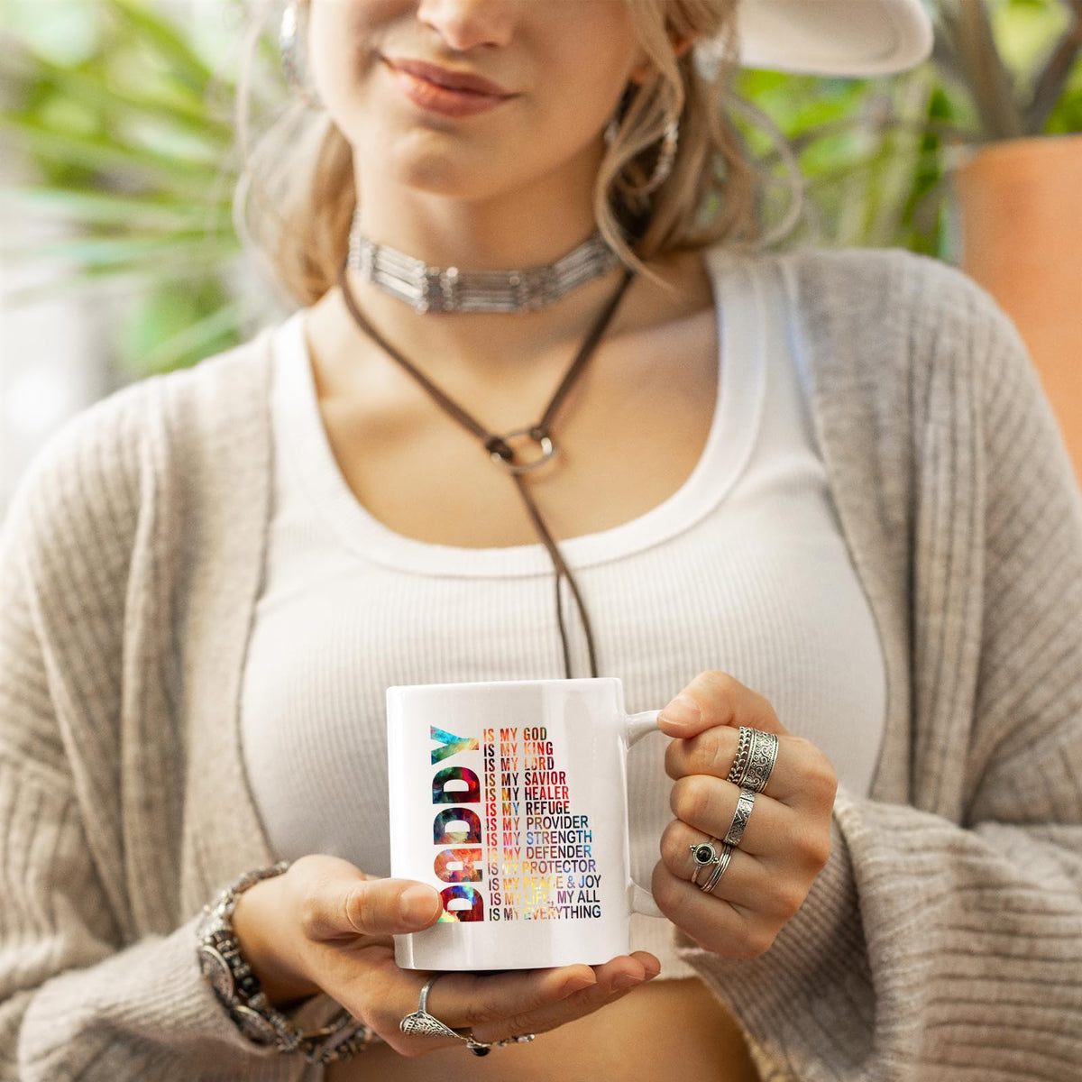 Woman in a cardigan holding the Daddy Is My God mug