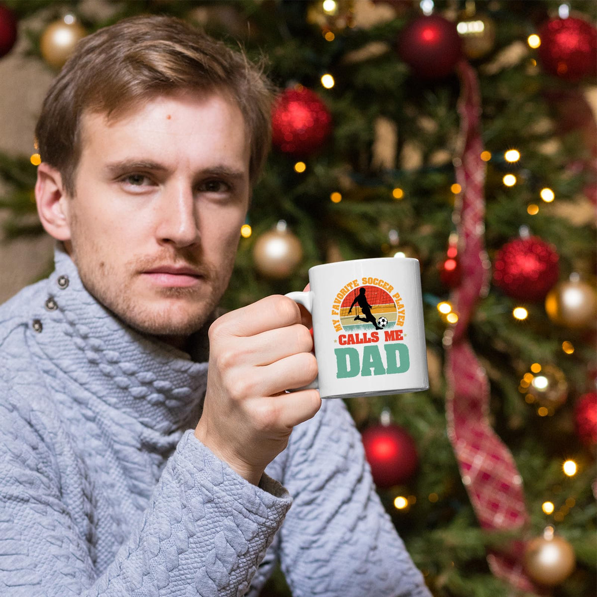 Man holding the Soccer Dad mug in front of a Christmas tree