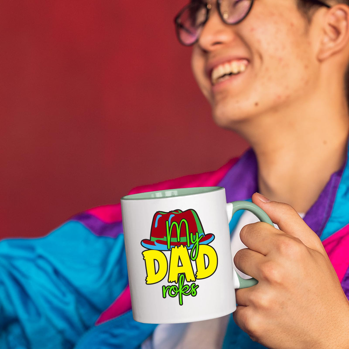 Person laughing while holding a lime handle mug with the colourful My Dad Rocks hat design