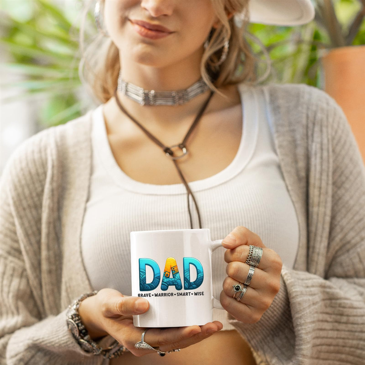 Woman in a cardigan holding the DAD Brave Warrior mug
