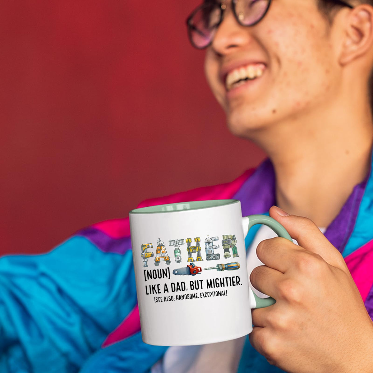 Smiling person in a colourful jacket holding the Father definition mug with a light green handle