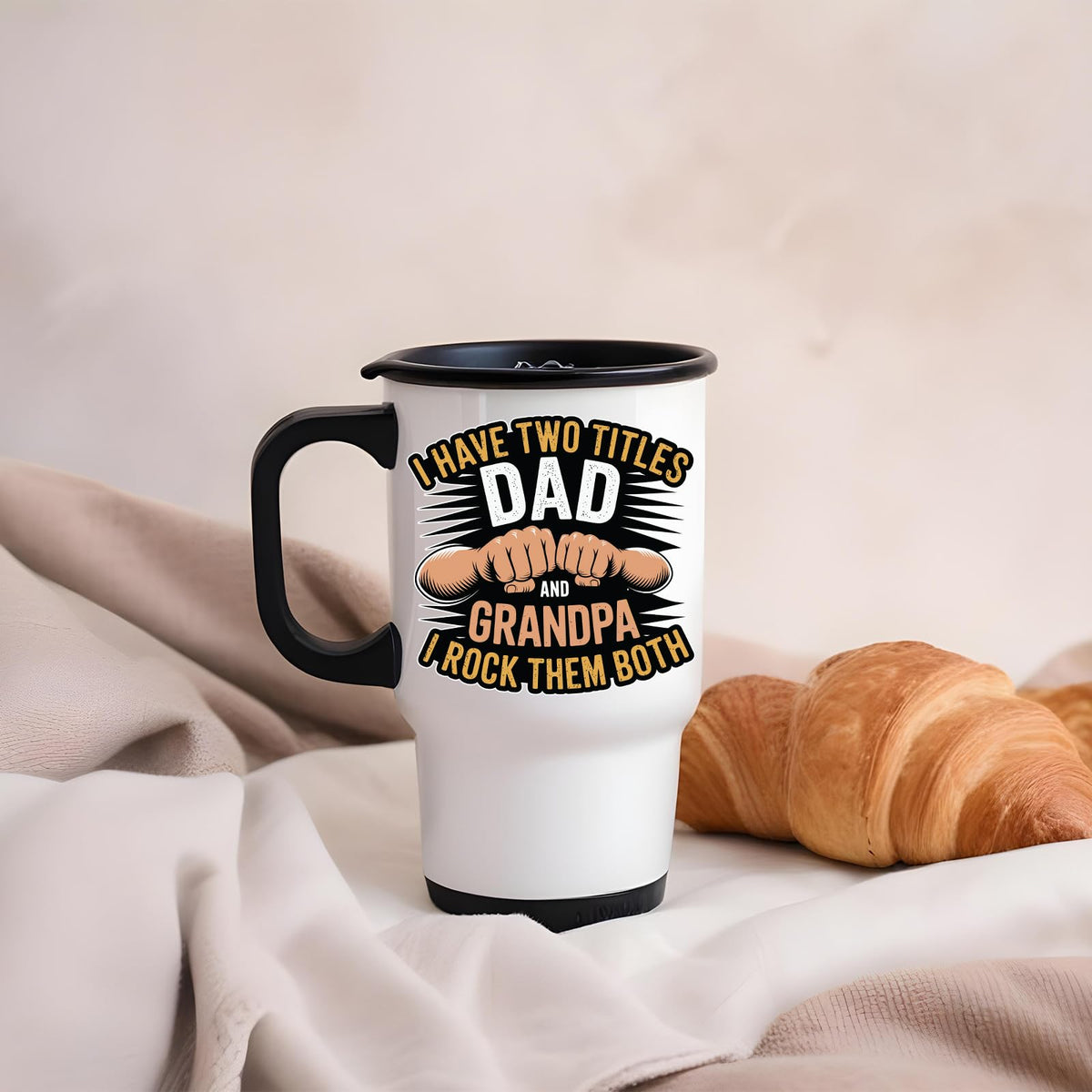 Two Titles Dad and Grandpa travel mug on a soft blanket beside a croissant