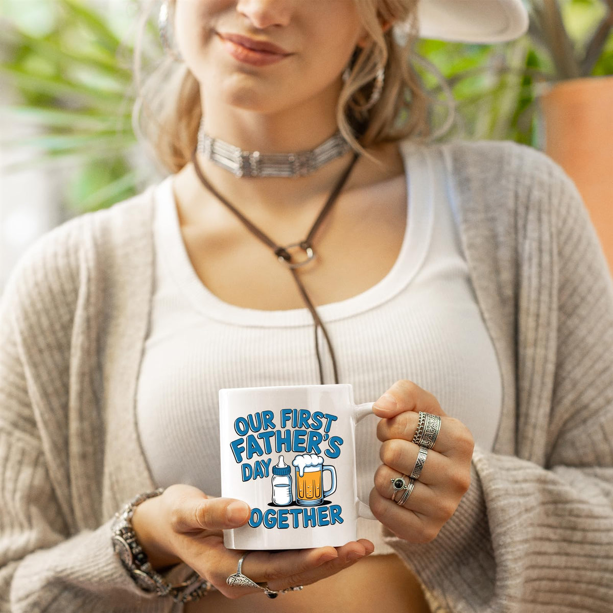 Woman in a cardigan holding the First Father’s Day bottle and beer mug