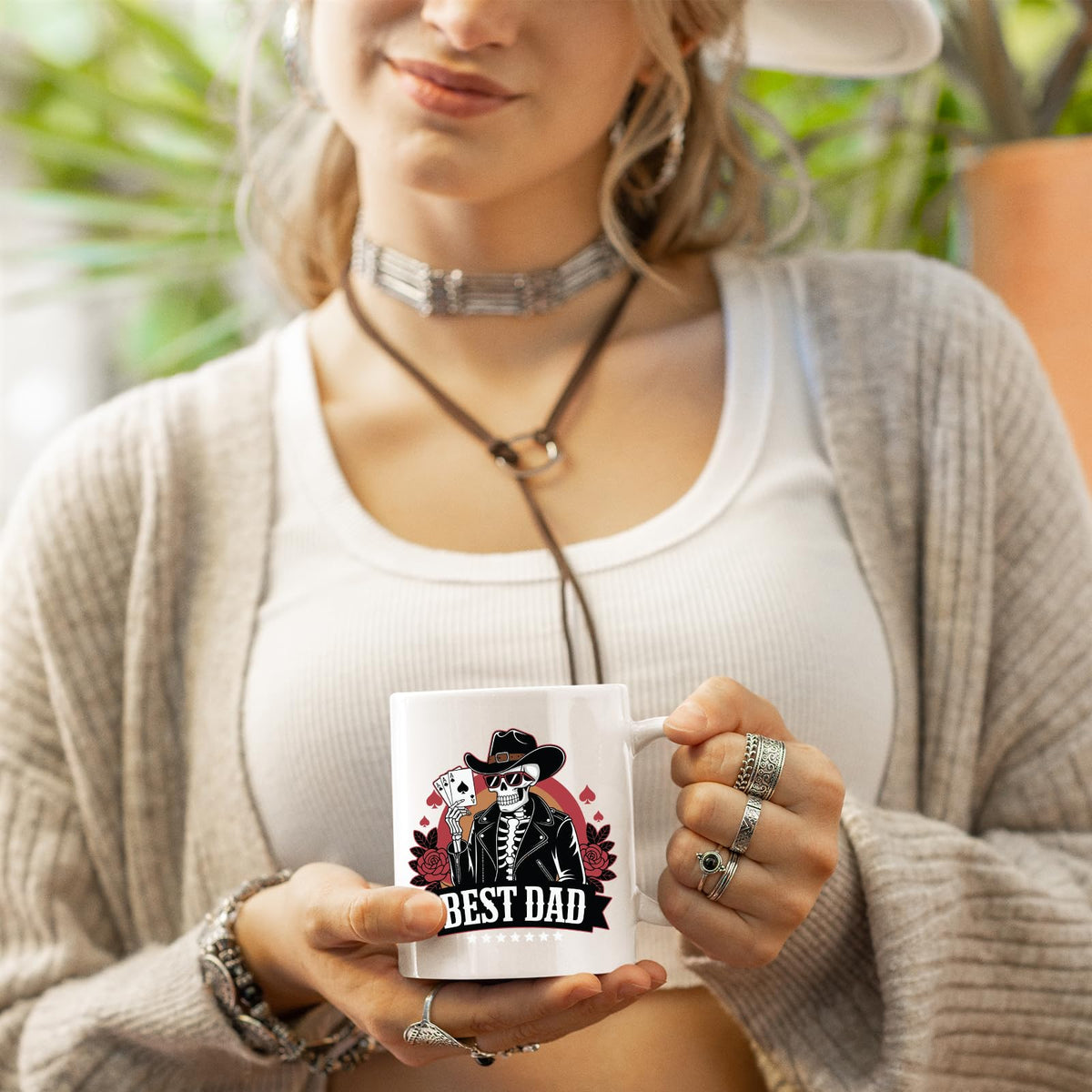 Woman in a cardigan holding the Best Dad skeleton cowboy mug