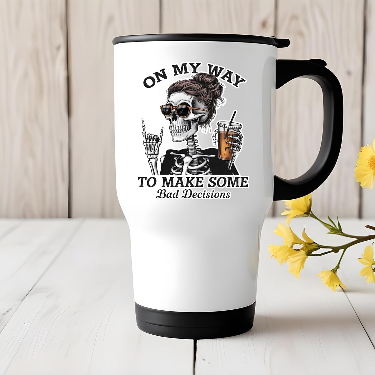 Bad Decisions skeleton travel mug on a white wooden table with yellow flowers