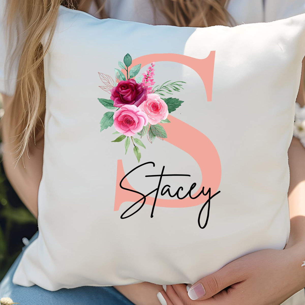 Woman hugging a cushion with a blush pink initial with roses and an example name
