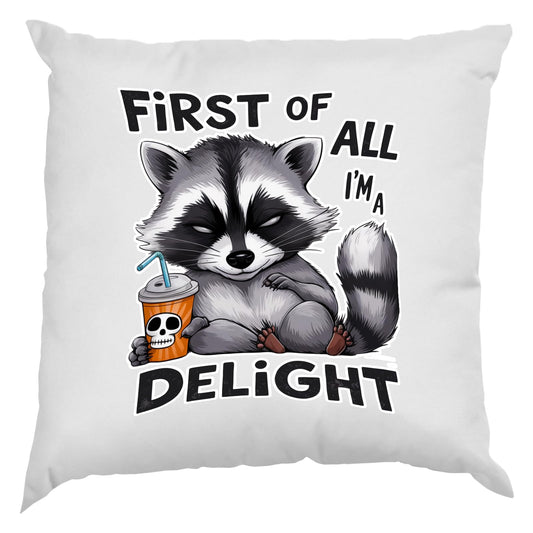 White cushion with a grumpy raccoon with a skull cup and “First of all I’m a delight”