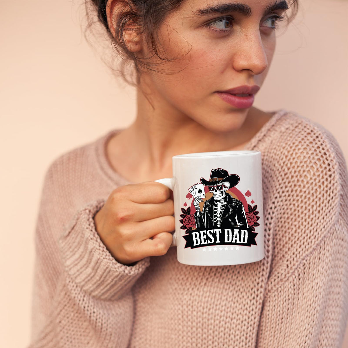 Woman in a pink jumper holding the Best Dad skeleton cowboy mug