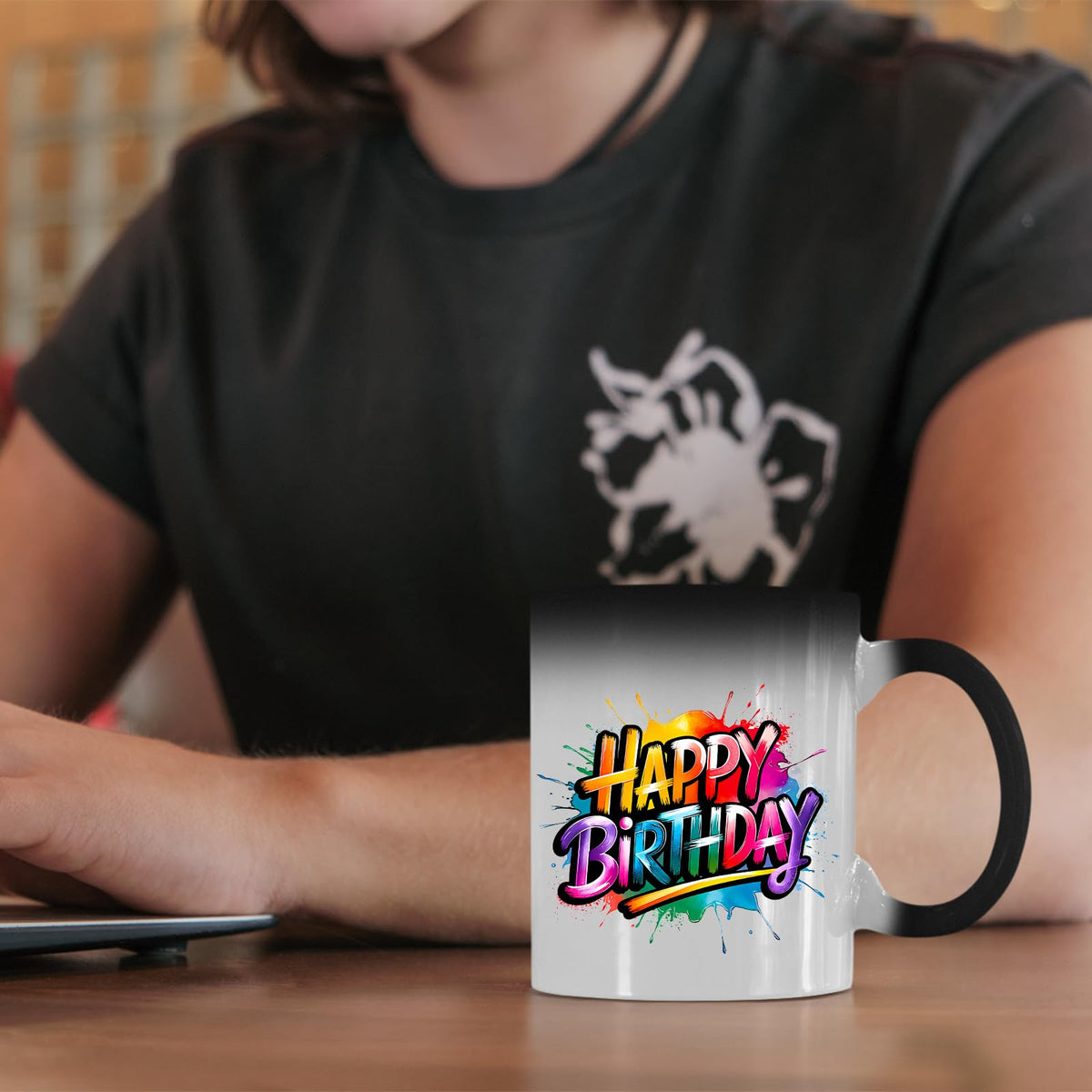 Happy Birthday rainbow splash colour changing mug on a desk beside a laptop