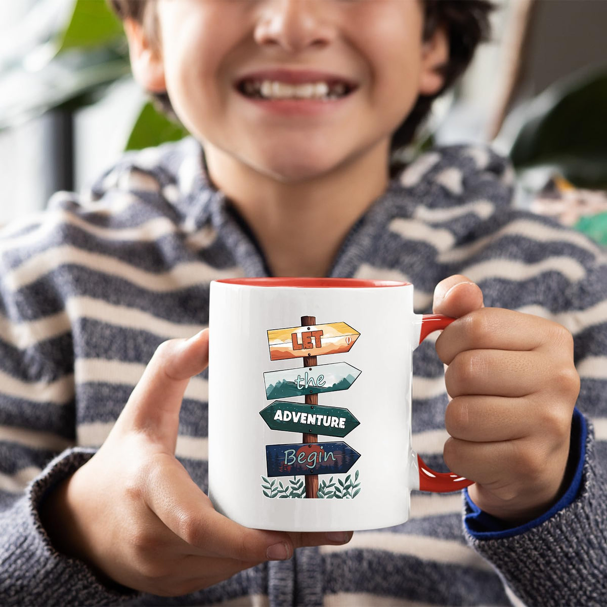 Smiling child holding the Let the Adventure Begin mug with a red handle