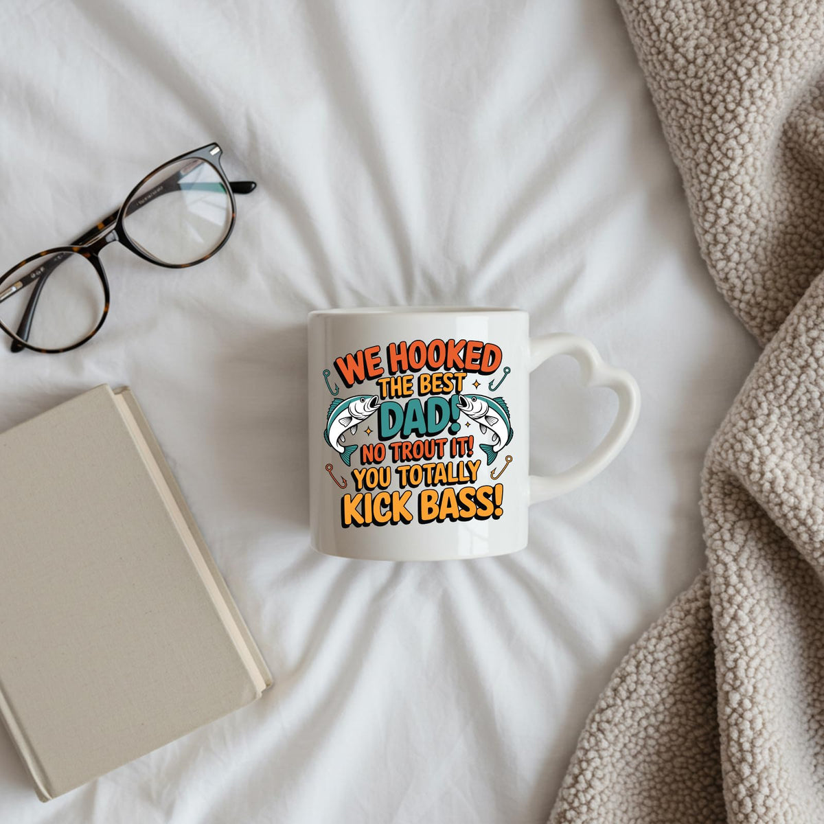 We Hooked the Best Dad heart-handle mug on a bed beside glasses and a book