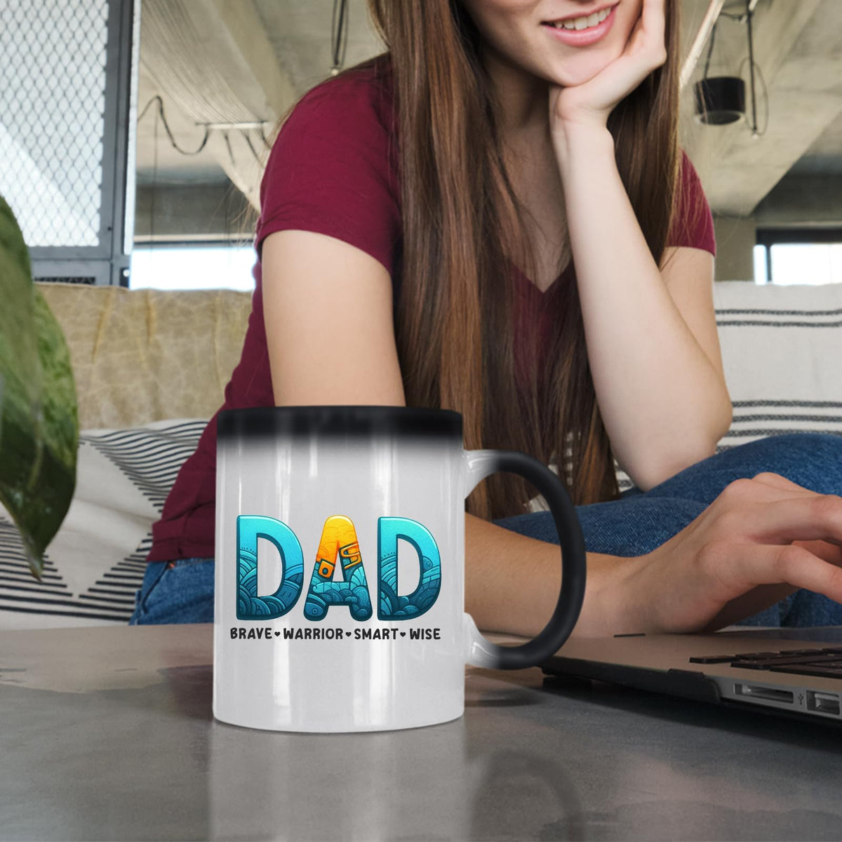 Woman at a laptop with the DAD Brave Warrior colour changing mug