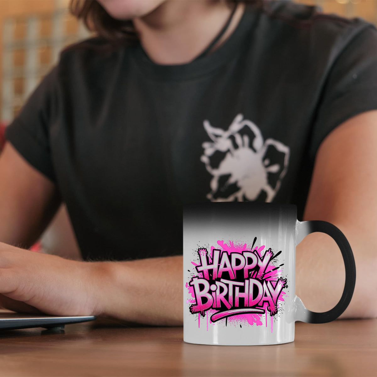 Happy Birthday pink graffiti colour changing mug on a desk beside a laptop