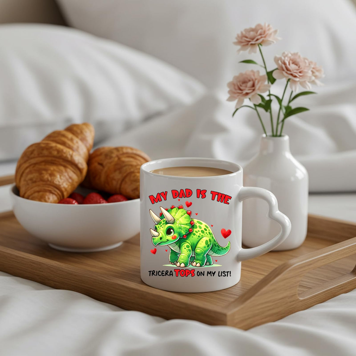 Triceratops dad heart-handle mug on a breakfast tray with croissants and flowers