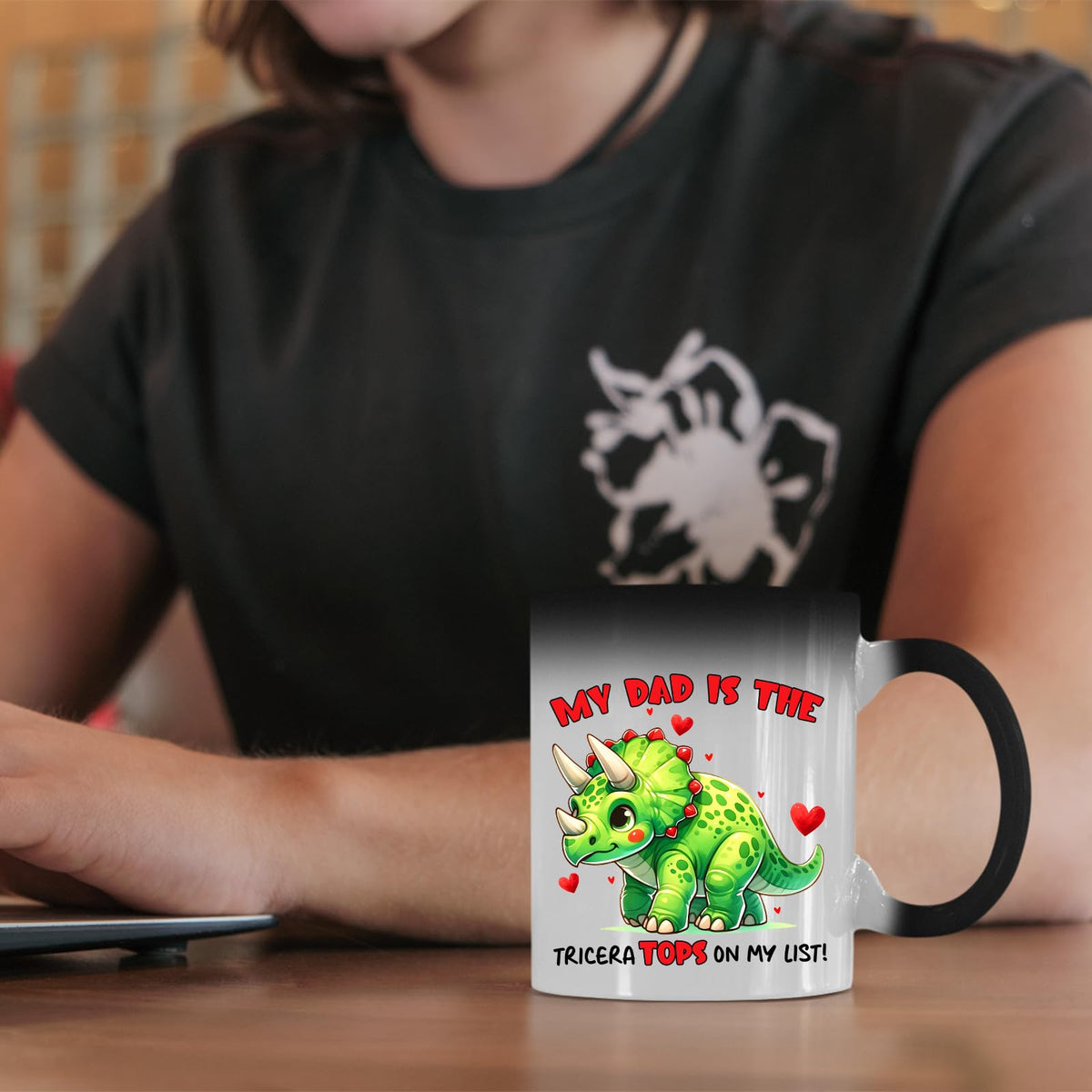 Triceratops dad colour changing mug on a desk beside a laptop