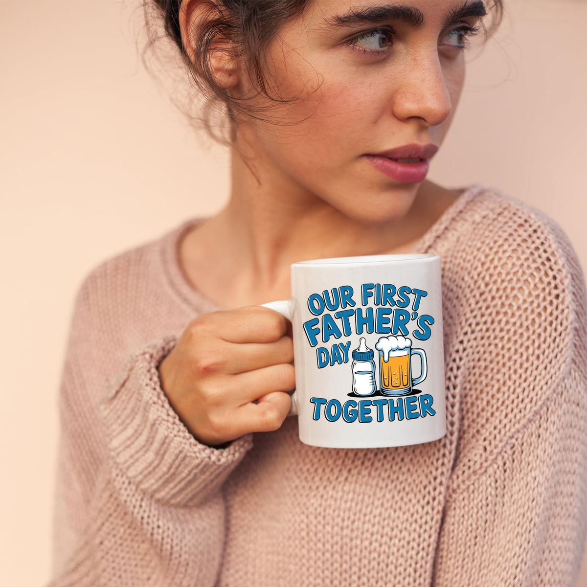 Woman in a pink jumper holding the First Father’s Day bottle and beer mug