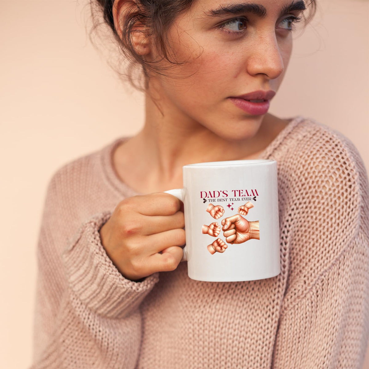 Woman in a pink jumper holding the Dad’s Team fist bump mug