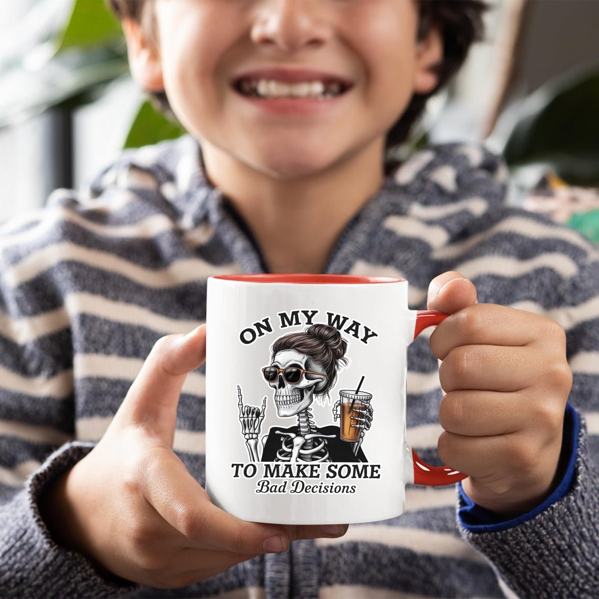 Smiling child holding the Bad Decisions skeleton mug with a red handle