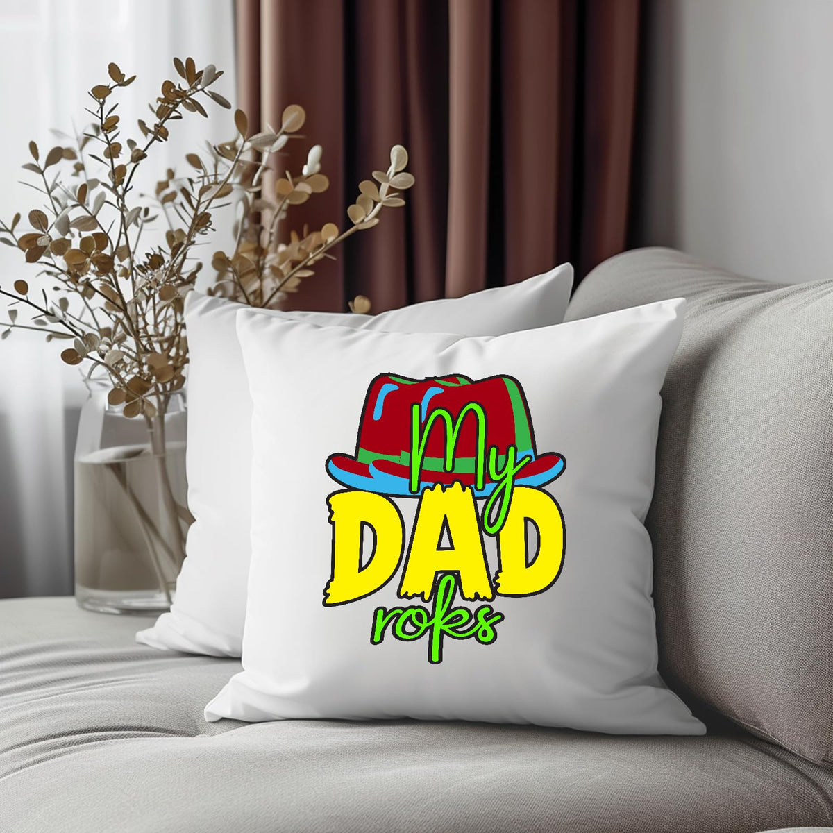 Cushion with the colourful My Dad Rocks hat design on a grey sofa