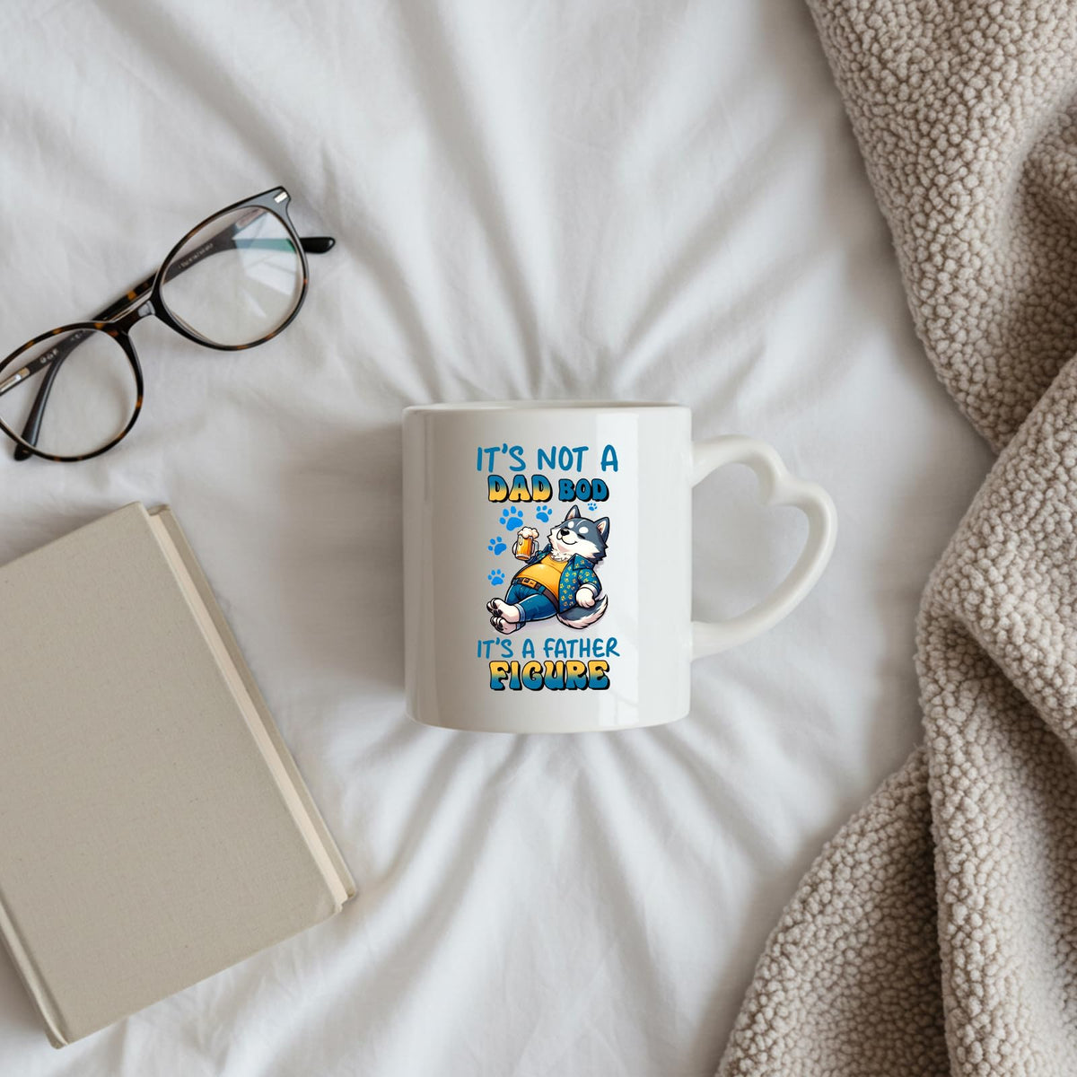 Dad Bod husky heart-handle mug on a bed beside glasses and a book